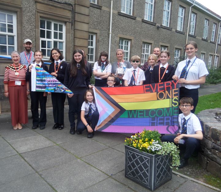 Students and Ulverston mayor stood with LGBTQ flag and Ulverston pride flag.