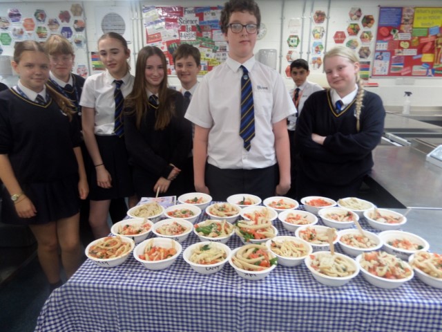 School students stood around bowls of pasta